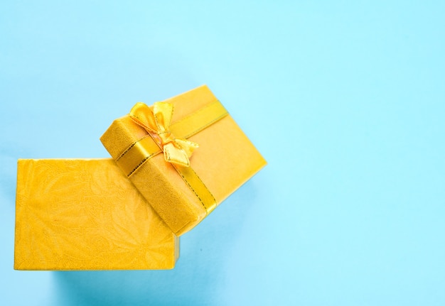 Yellow gift box with bow ribbon on the blue background