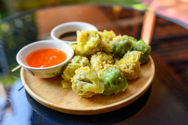 Yellow and green dumpling dim sum stuffed with pork and shrimp with sauces