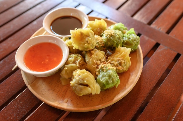 Yellow and green dumpling dim sum stuffed with pork and shrimp with sauces