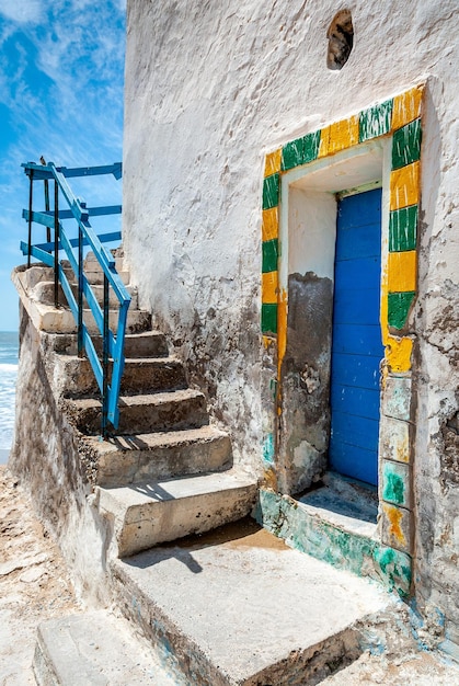 Yellow and green frame of a blue door on a decrepit white building in Sidi Kaouki Morocco