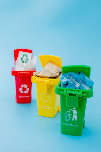 Yellow, green and red recycle bins with recycle symbol on blue wall. Keep city tidy, Leaves the recycling symbol. Nature protection concept.