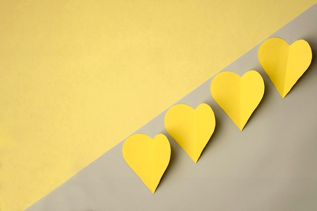 Yellow hearts cut out of colored paper on a yellow background, top view. Monochrome colored valentines day concept.