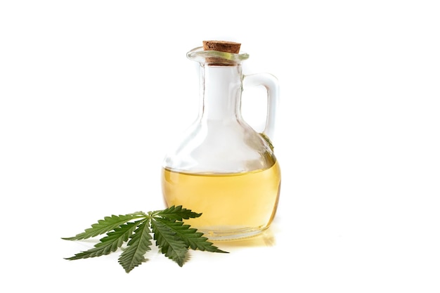 Yellow hemp oil in a bottle with a wooden stopper with a green leaf of the cannabis plant