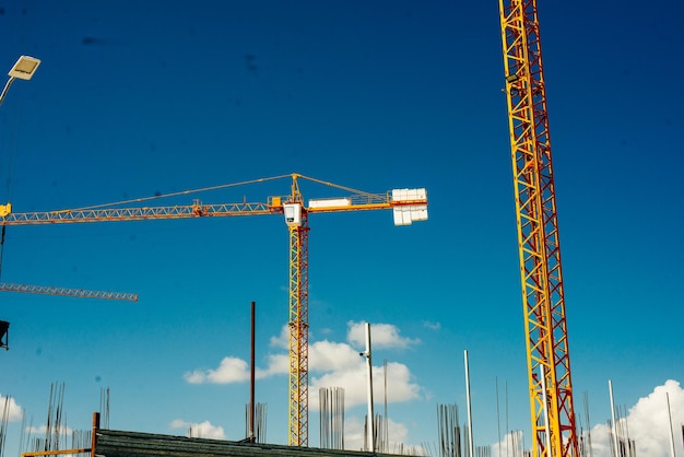 Yellow Industrial Cranes Working on Construction Site Against Blue Sky