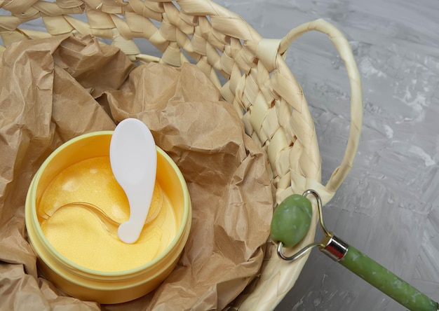 Yellow jar of golden eye patches and face massage roller lie in a wicker basket decongestant