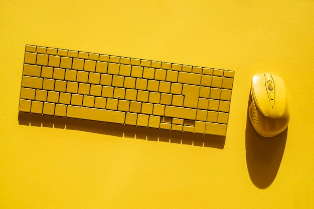 Yellow keyboard and yellow computer mouse on a yellow background Top view flat lay