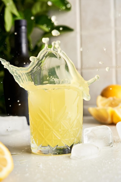 Yellow lemon Limoncello liqueur cocktail with splash drops at kitchen background.