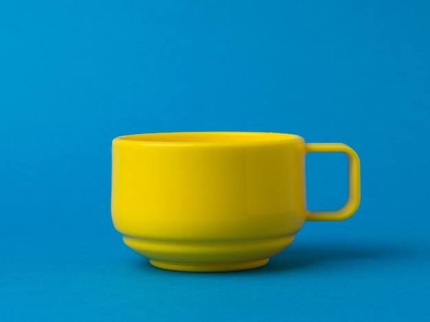 Yellow low bowl on a bright blue background. The style of minimalism.