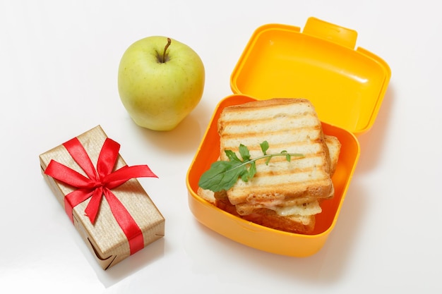 Yellow lunch box with toasted slices of bread cheese and green apple