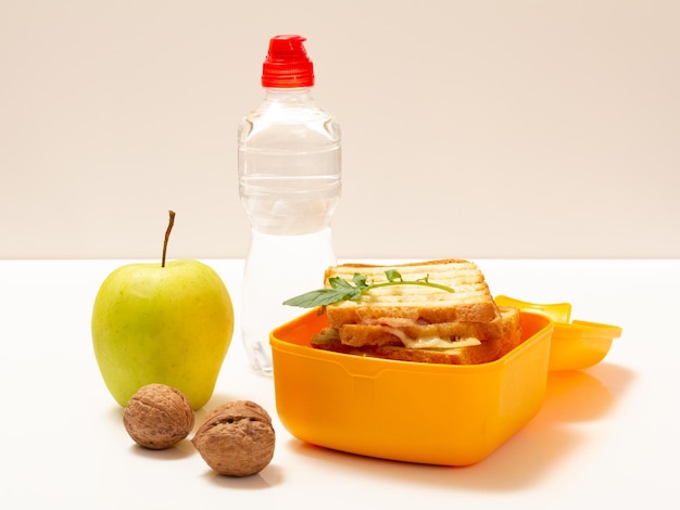 Yellow lunch box with toasted slices of bread cheese and green parsley