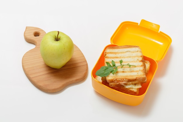 Yellow lunch box with toasted slices of bread cheese and green parsley