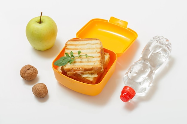 Yellow lunch box with toasted slices of bread cheese and green parsley