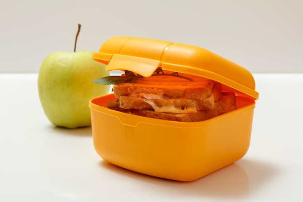 Yellow lunch box with toasted slices of bread cheese and green parsley