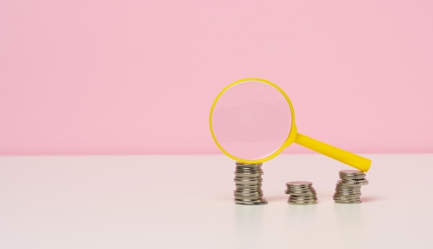 Yellow magnifier and white coins on the table. Income growth concept, high percentage of investment. Search for new sources of income, subsidy