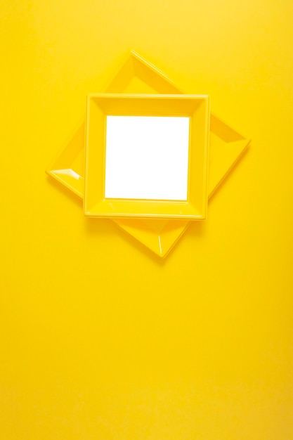 Yellow modern photo frame on yellow wall with rhombus shape Copy space