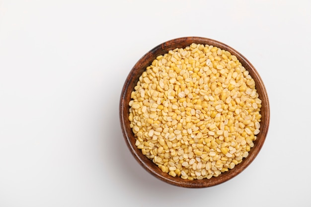 Yellow moong mung dal lentil pulse bean in wooden bowl on white background