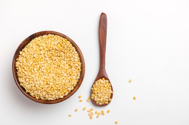 Yellow moong mung dal lentil pulse bean in wooden spoon on white background