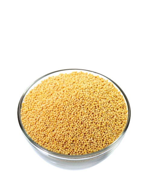 Yellow mustard seeds in glass bowl isolated on white background