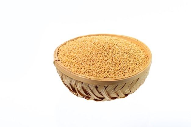 Yellow mustard seeds in wooden basket isolated on white