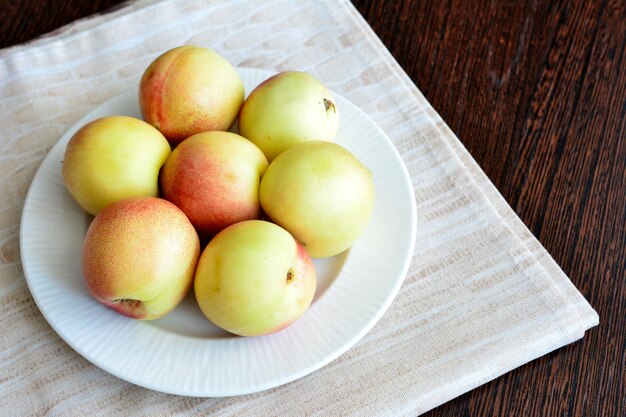 yellow nectarines on white plate isolated on kitchen napkin, close-up