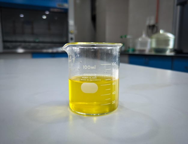 Photo the yellow oil and chemical liquid that had been mixed in a beaker were on the table of a laboratory in a factory