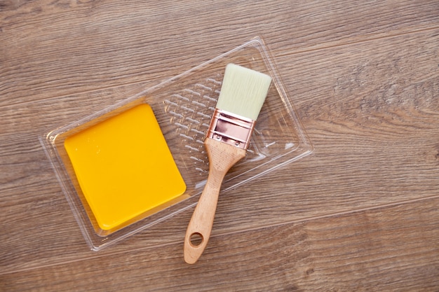 Yellow paint on wooden brown floor, brush