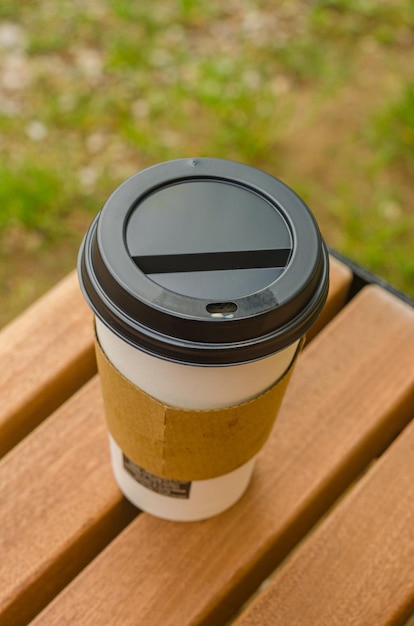 Photo yellow paper coffee cup on wooden bench high quality photo