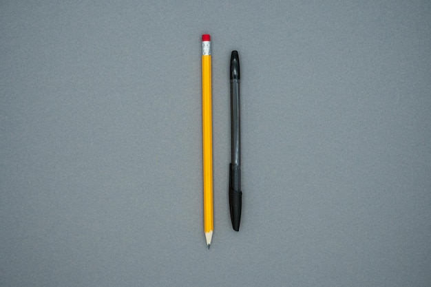 Yellow pencil and black pen on a gray background. Education or business concept