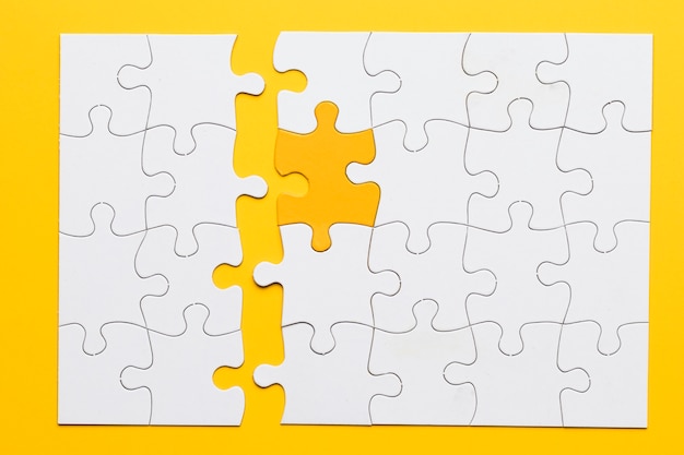 Yellow piece connect with white puzzle pieces on plain background