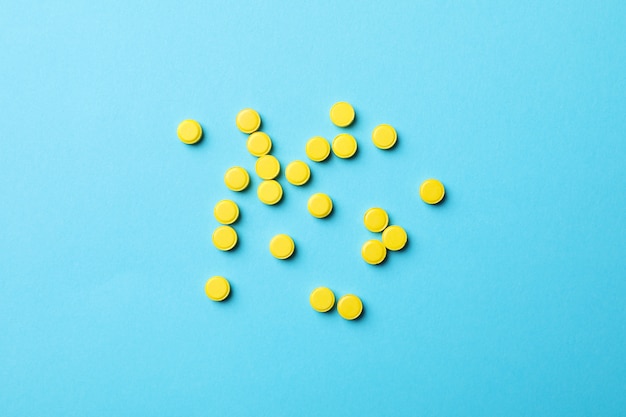 Yellow pills on blue background, top view and space for text