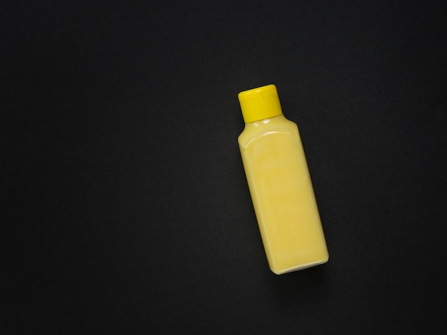 A yellow plastic bottle with a yellow liquid on a black background