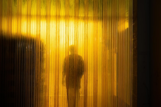 Yellow plastic curtain entrance with shadow of worker and cardboard package in warehouse