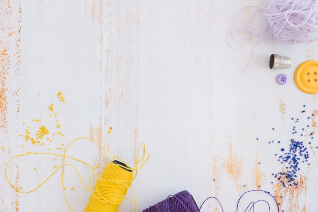 Yellow and purple yarn spool and beads on white desk