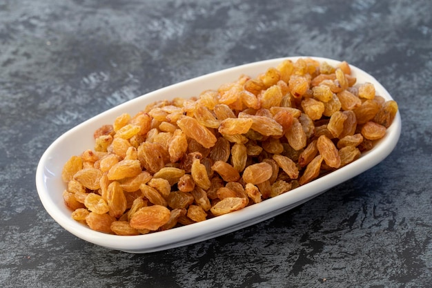 Yellow Raisins on plate on dark background