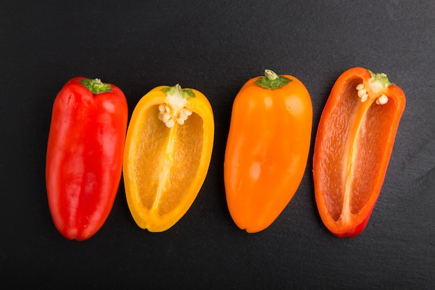 yellow, red, orange sweet peppers  on a black slate surface. top view, close up.