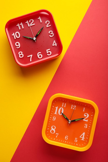 Yellow and red wall clock on yellow and red background Vertical photo