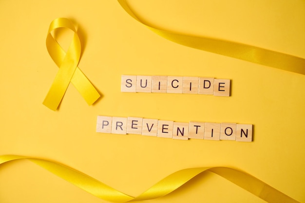 Photo yellow ribbon symbol of the world suicide prevention day on yellow flat background