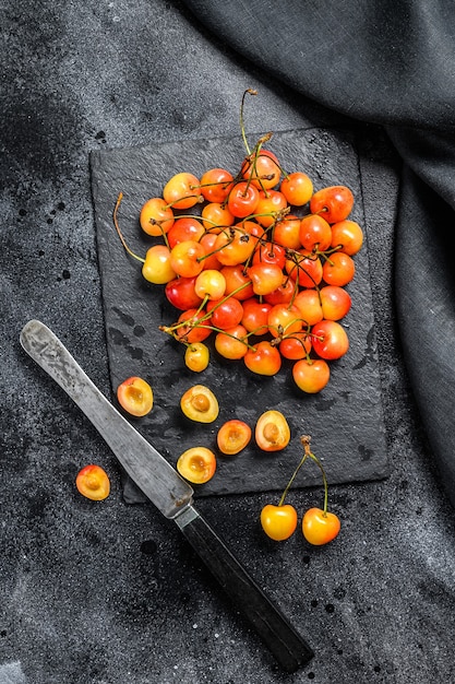 Yellow ripe cherries on a black plate