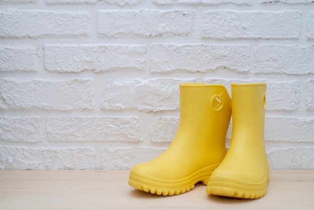 Yellow rubber boots against a white brick wall