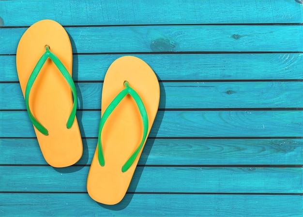 Yellow rubber sandals flip flops on wooden background