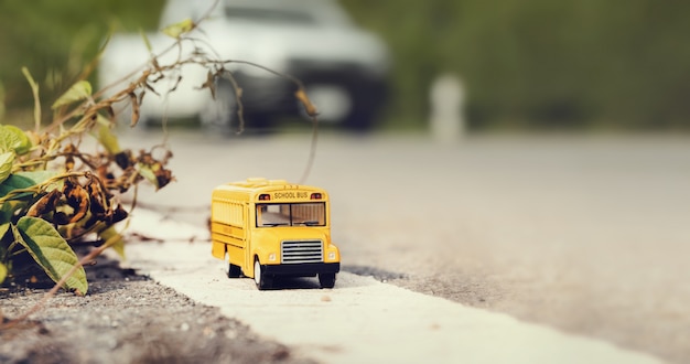 Yellow school bus toy model on country road.