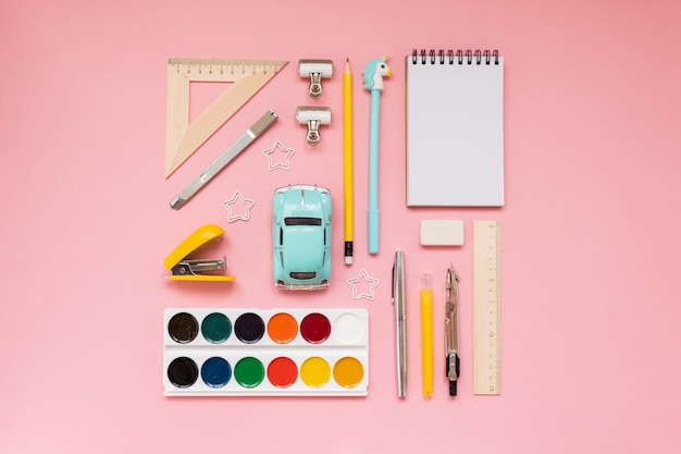 Yellow school supplies on pastel pink background