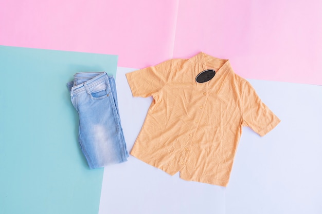 A yellow shirt and blue jeans on a background of various pastel colors