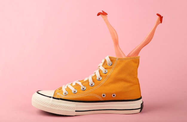 Yellow sneaker with doll legs on a pink background Minimalism Concept art