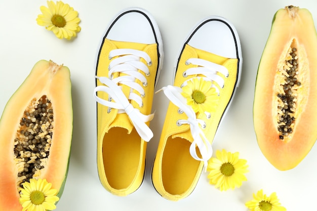 Yellow sneakers with flowers and papaya on white background