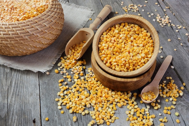 Yellow split peas in a wooden bowl on a gray table