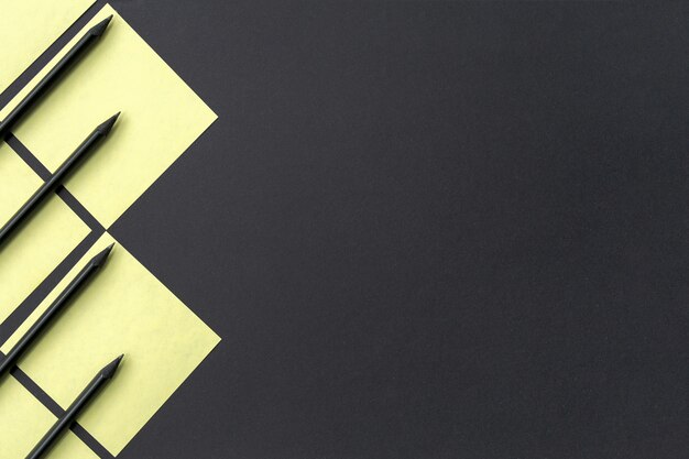 Yellow stickers with black pencils lined with a geometric pattern on black