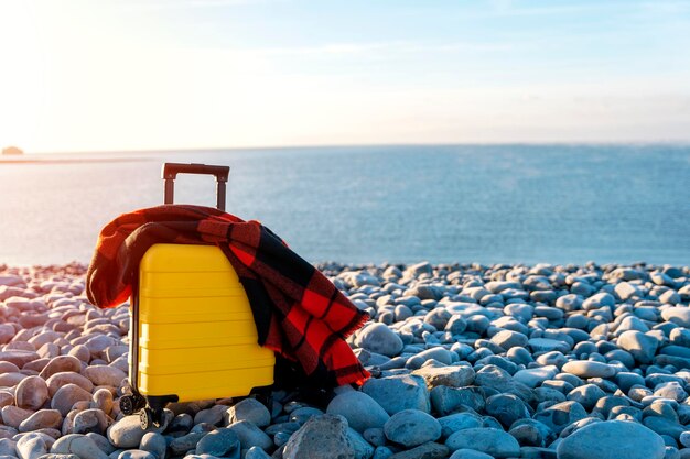 Yellow Suitcase with orange scarf on seaside Travel concept