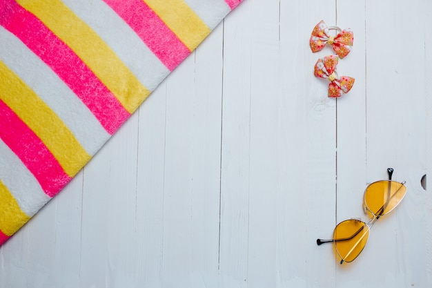 Yellow sunglasses and striped colorful towel on the white wood