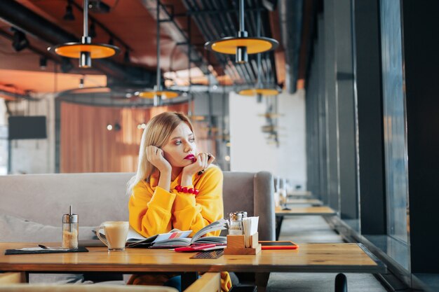 Yellow sweater Beautiful stylish woman wearing yellow sweater and red bracelet looking into window